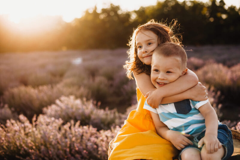 children hugging in a field smiling and comforting each other