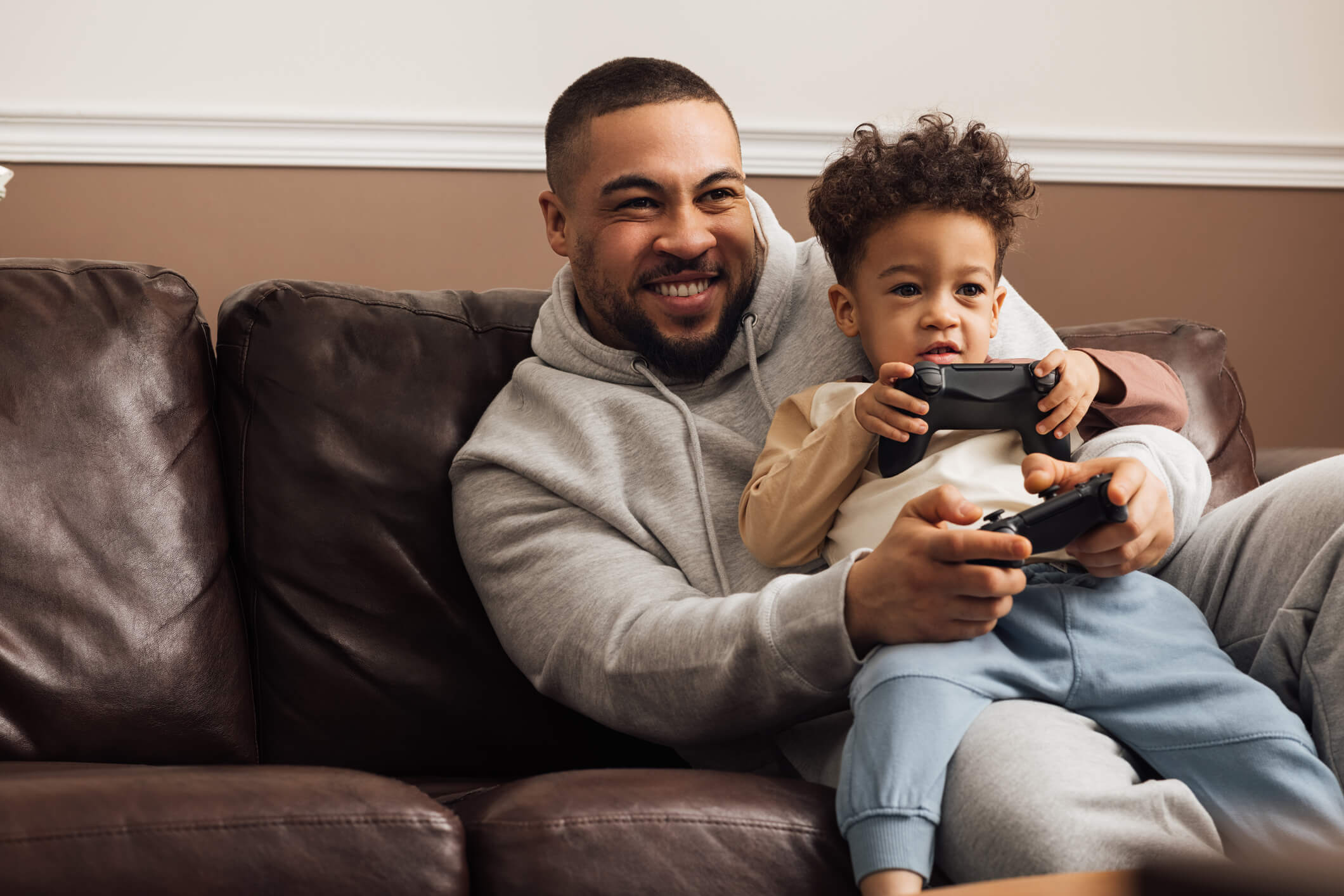foster parent playing video games and smiling with child