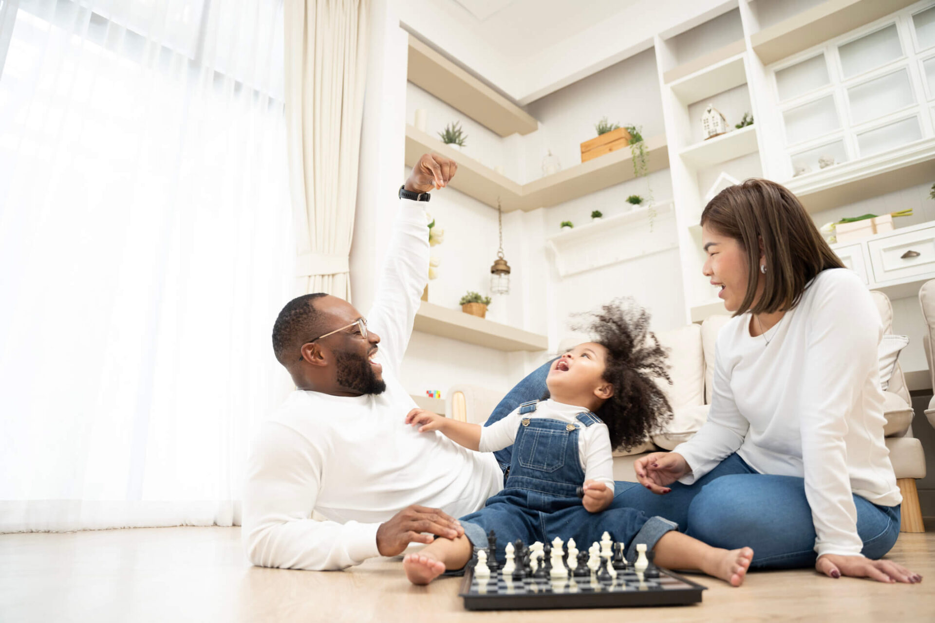 happy foster parents playing chess with child smiling