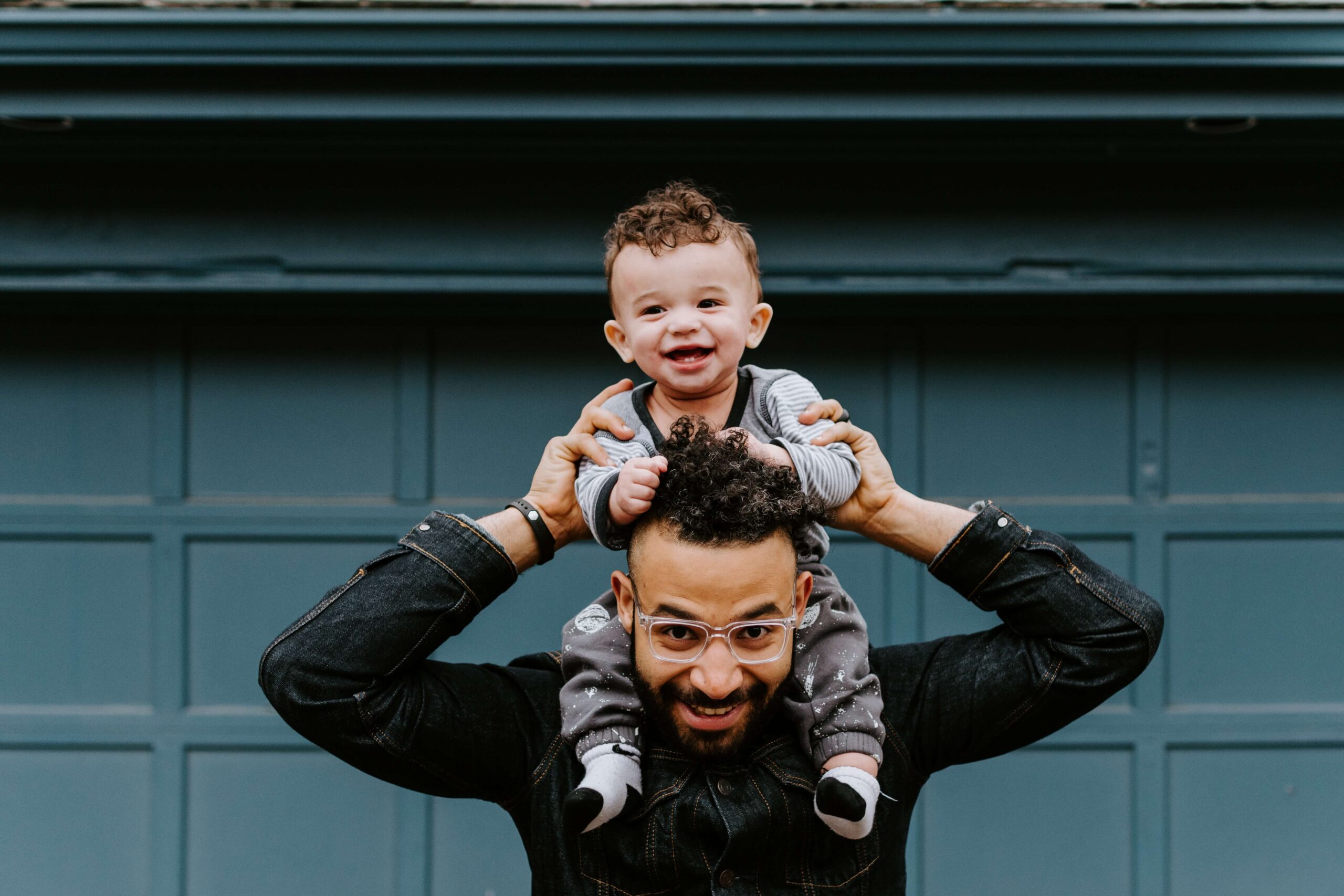 foster parent holding child on his shoulders smiling